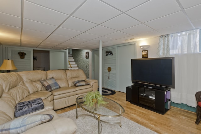 living area featuring stairway, a drop ceiling, and wood finished floors