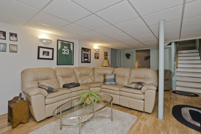 living area with a paneled ceiling, stairs, and wood finished floors