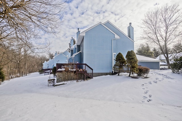 view of snow covered exterior featuring a chimney and a wooden deck