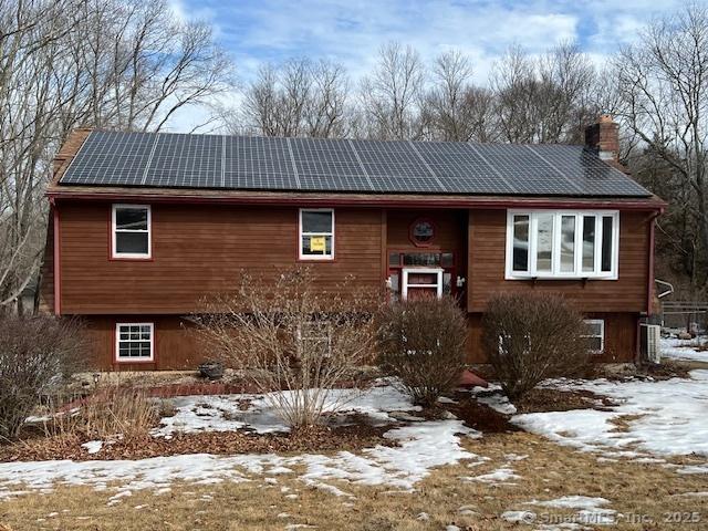 view of front of home with roof mounted solar panels and a chimney