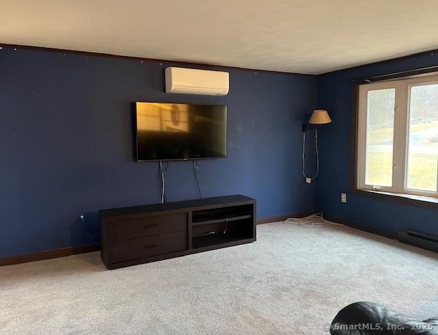 unfurnished living room with baseboards, an AC wall unit, and carpet flooring