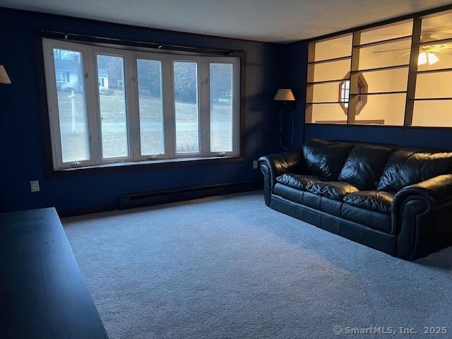 carpeted living room with a baseboard heating unit