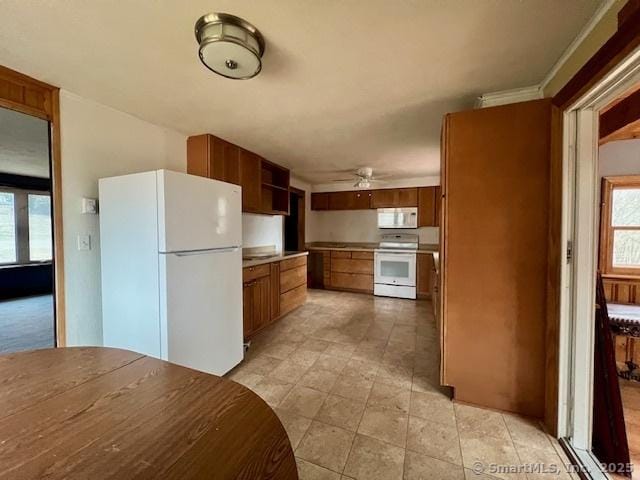 kitchen with ceiling fan, light countertops, white appliances, and brown cabinetry