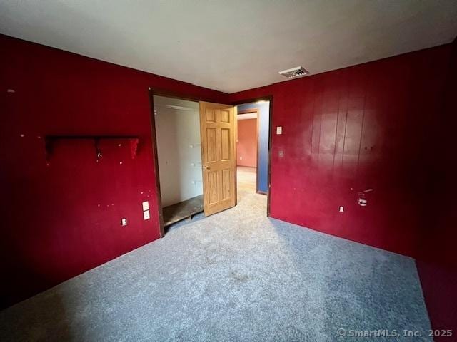 unfurnished bedroom with carpet, visible vents, and a closet