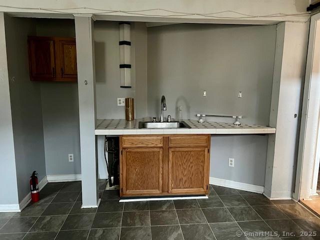 bar featuring a sink, dark tile patterned floors, and baseboards