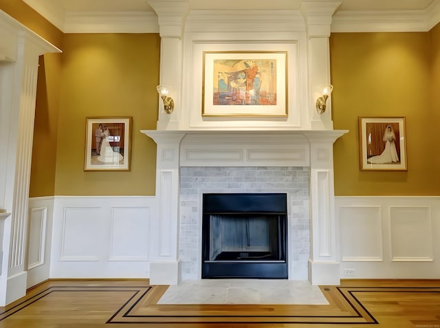 room details featuring a decorative wall, wainscoting, a fireplace, and crown molding