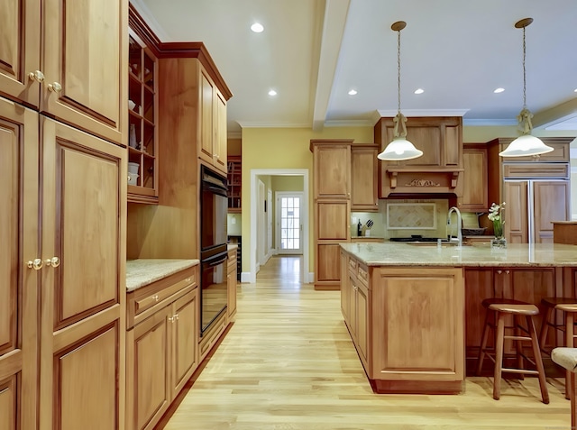 kitchen with light wood finished floors, backsplash, crown molding, a breakfast bar, and paneled refrigerator