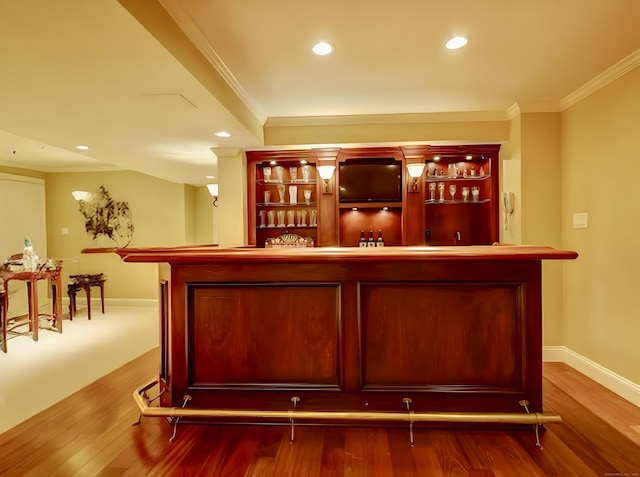 bar featuring crown molding, baseboards, recessed lighting, wet bar, and wood finished floors