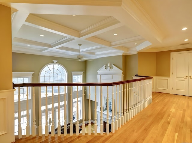 hall featuring beamed ceiling, light wood-type flooring, ornamental molding, wainscoting, and coffered ceiling