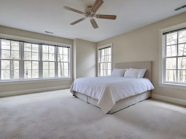 carpeted bedroom with visible vents, baseboards, and a ceiling fan