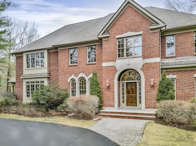 view of front of house featuring brick siding and roof with shingles