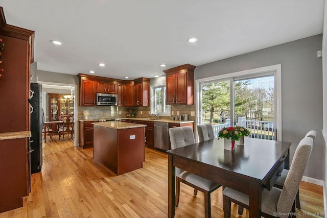 kitchen featuring decorative backsplash, appliances with stainless steel finishes, a center island, and light wood finished floors