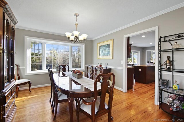 dining room with an inviting chandelier, crown molding, light wood-style floors, and baseboards