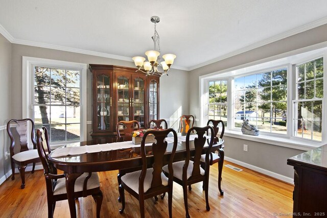 dining room with visible vents, a healthy amount of sunlight, ornamental molding, and an inviting chandelier