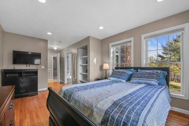 bedroom with light wood finished floors, recessed lighting, and baseboards