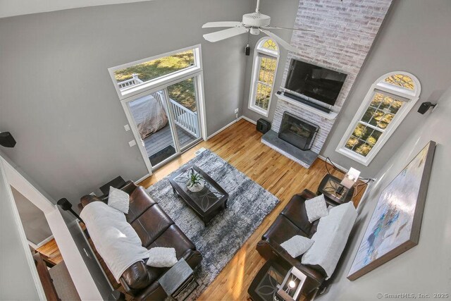 living room with baseboards, high vaulted ceiling, a brick fireplace, and wood finished floors