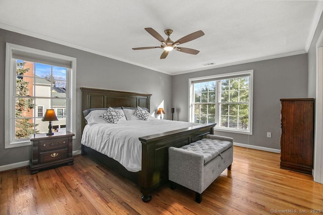 bedroom with visible vents, multiple windows, baseboards, and wood finished floors