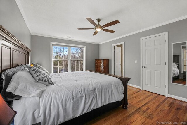 bedroom with visible vents, crown molding, baseboards, and wood finished floors