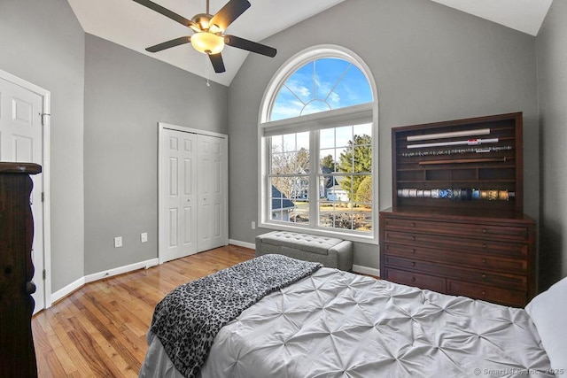 bedroom featuring baseboards, wood finished floors, a closet, high vaulted ceiling, and a ceiling fan