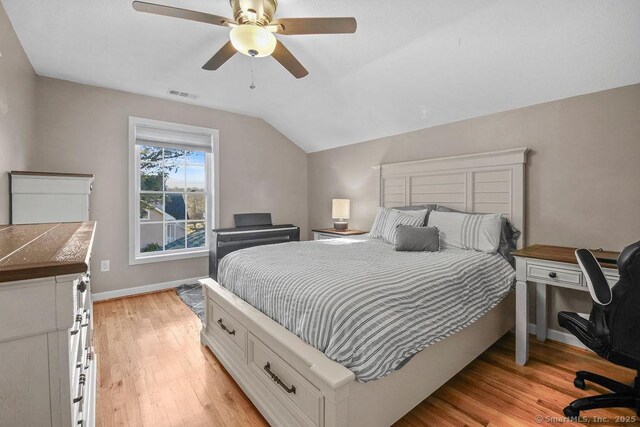 bedroom with visible vents, a ceiling fan, light wood-style floors, baseboards, and vaulted ceiling