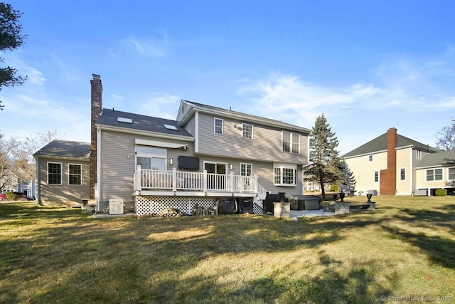 rear view of property featuring a lawn, a chimney, and a wooden deck