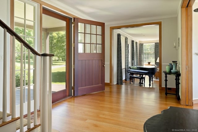 foyer with light wood-style floors and crown molding