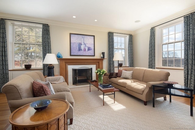 living room with a healthy amount of sunlight, a fireplace with flush hearth, and crown molding