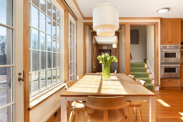 dining area featuring visible vents, crown molding, light wood finished floors, and stairs