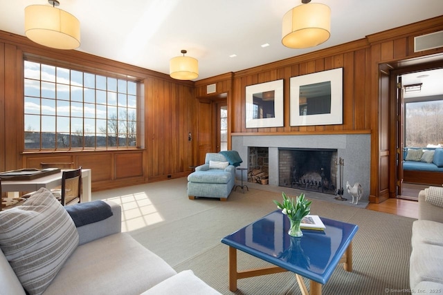 living area featuring crown molding, light carpet, a fireplace, and wood walls