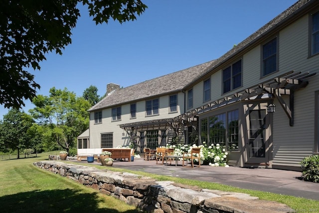 back of property featuring a patio, a yard, a chimney, a pergola, and a high end roof