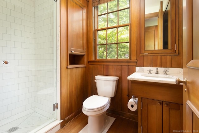 full bathroom with a stall shower, toilet, wood finished floors, vanity, and wood walls