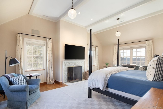 bedroom featuring vaulted ceiling with beams, a fireplace, baseboards, and wood finished floors