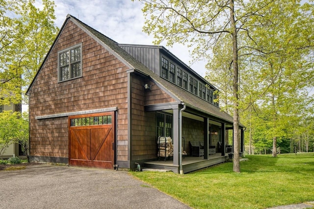 exterior space with an outbuilding, roof with shingles, a lawn, a barn, and driveway