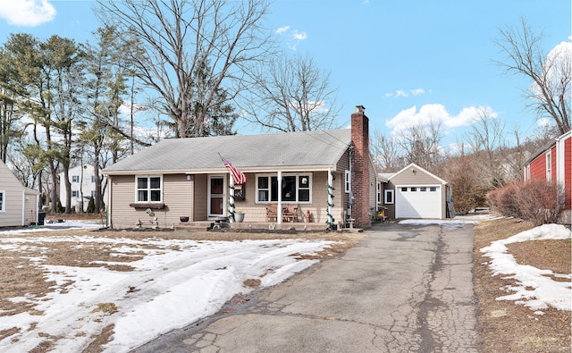 view of front of home with a detached garage, aphalt driveway, a porch, a chimney, and an outdoor structure