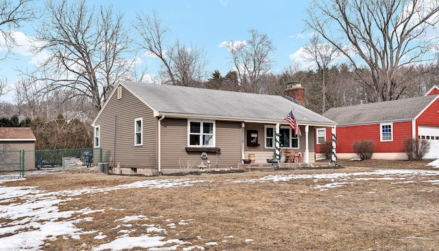 view of front of property with fence, covered porch, a chimney, an outdoor structure, and a garage