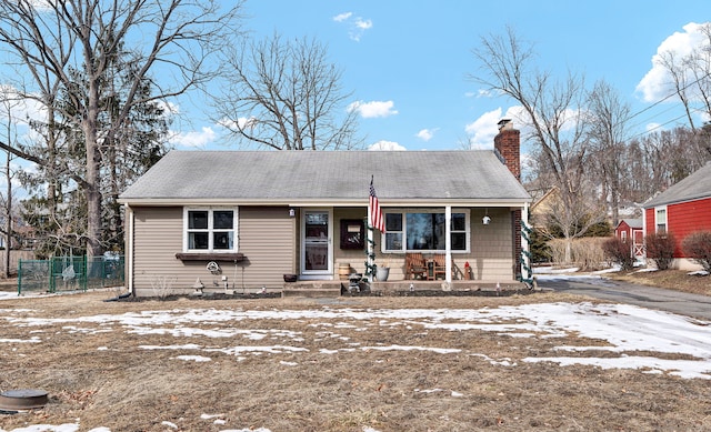 view of front of home featuring fence, covered porch, and a chimney