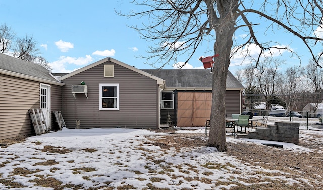 snow covered house with a wall mounted air conditioner