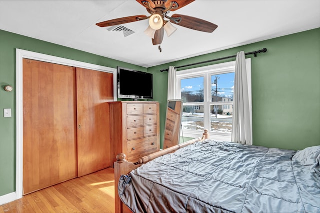 bedroom with a closet, visible vents, light wood-type flooring, and a ceiling fan