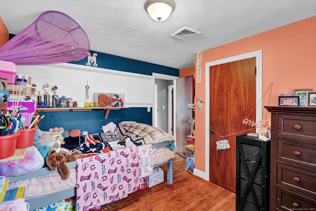 bedroom with wood finished floors and visible vents