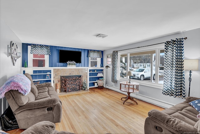 living room with visible vents, a baseboard radiator, wood finished floors, and a premium fireplace