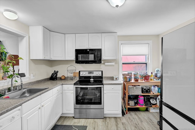 kitchen featuring light wood finished floors, black microwave, stainless steel range with electric stovetop, white dishwasher, and a sink