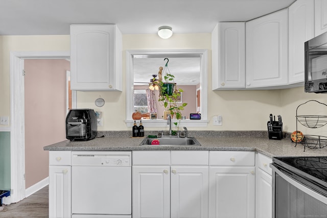 kitchen with dishwasher, white cabinetry, black microwave, and a sink