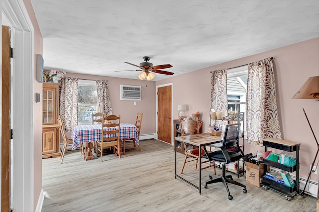 interior space with a baseboard heating unit, light wood-style flooring, a ceiling fan, and a wall mounted air conditioner