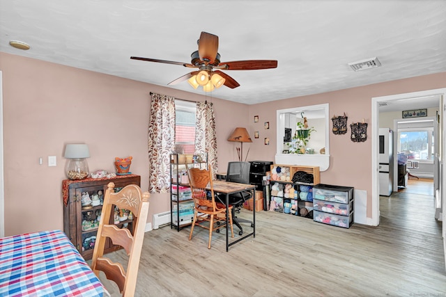 interior space with baseboards, wood finished floors, visible vents, and ceiling fan