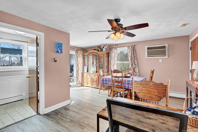 dining space featuring a baseboard heating unit, light wood-style flooring, baseboards, and a wall mounted AC