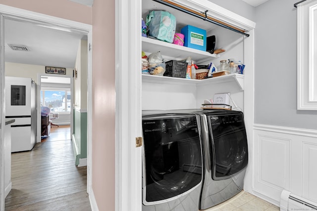 washroom featuring washer and clothes dryer, visible vents, laundry area, and a baseboard radiator