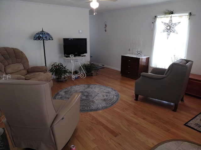 living area with light wood-style floors, ceiling fan, and ornamental molding