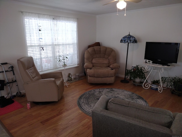 living room with crown molding, ceiling fan, and wood finished floors