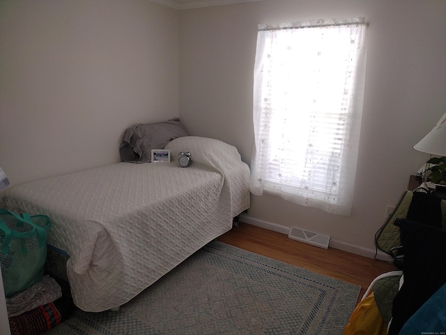 bedroom featuring baseboards, visible vents, and wood finished floors