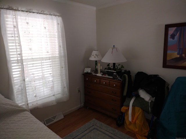 bedroom featuring ornamental molding, wood finished floors, visible vents, and baseboards